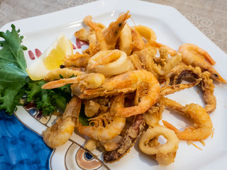 delicious Mediterranean dish of fried fish, sea food, calamari and shrimp with an ornamental lettuce leaf in a delicious dish of an Italian restaurant