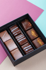 Assortment of luxury bonbons in box on colorful purple and blue background