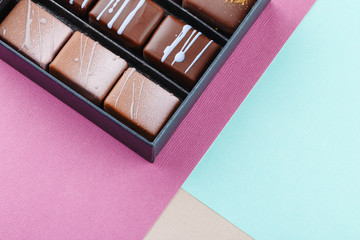 Assortment of luxury bonbons in box on colorful purple and blue background