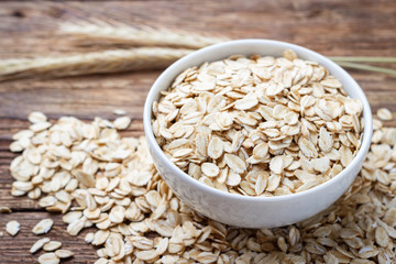 Dry rolled oat flakes oatmeal on wooden table