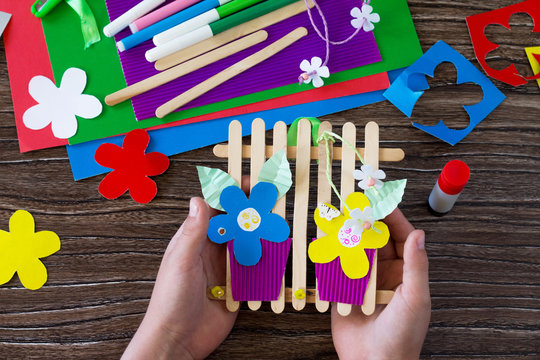 A gift of summer flowers on wooden sticks a fence on a wooden table. Handmade. Project of children's creativity, handicrafts, crafts for kids.