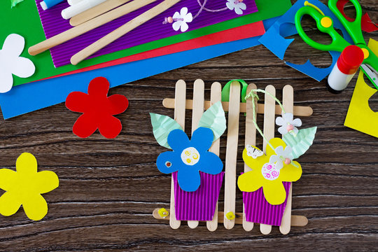 A gift of summer flowers on wooden sticks a fence on a wooden table. Handmade. Project of children's creativity, handicrafts, crafts for kids.
