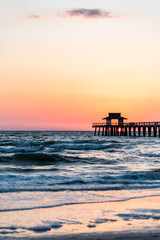 Naples, Florida pink and orange sunset vertical view in gulf of Mexico with sun setting inside Pier...