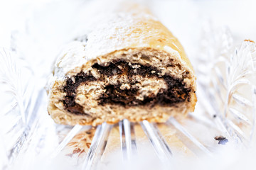 Closeup cut cross section of golden baked whole poppy seed roll cake, or chocolate babka pastry bread on table in crystal glass dish for festive traditional holiday