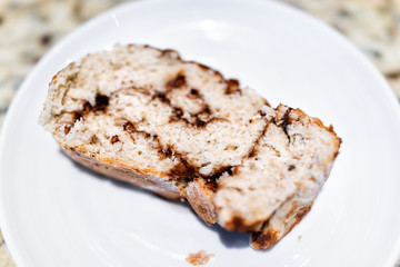 Macro closeup of homemade healthy vegan golden baked whole cinnamon roll cake slice bread on plate table