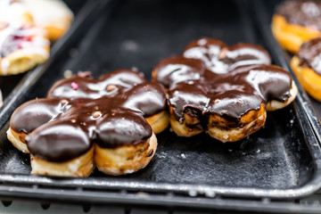 Chocolate flower shaped icing donuts closeup on bakery tray, deep fried vanilla, delicious tasty