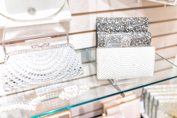 Closeup of many wedding luxury expensive shiny white purses in boutique discount store, selection on shelf display with glittering rhinestones