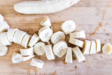 Chopped frozen banana flat top view down on wooden bamboo chopping board closeup