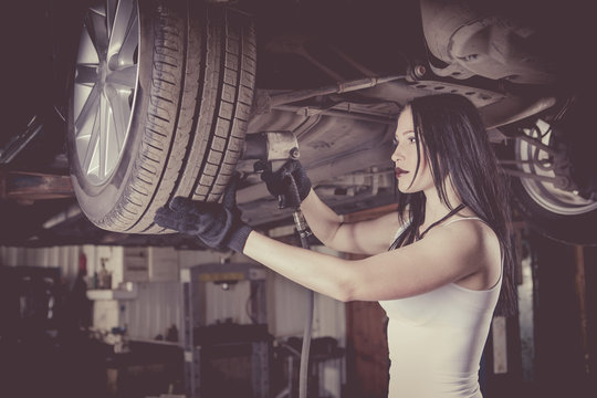 Woman mechanic is repairing a car on the lift.