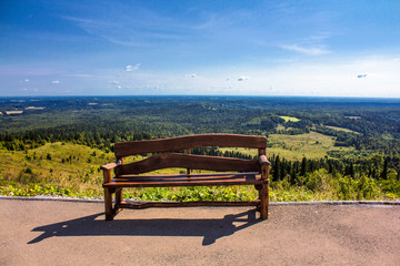 bench on a hill in open space and clouds