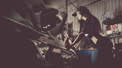 Women mechanics are inspecting the engine at the service station.