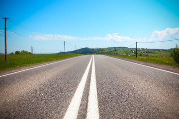 Fototapeta premium Asphalt road in a rural landscape. Road, village and sky