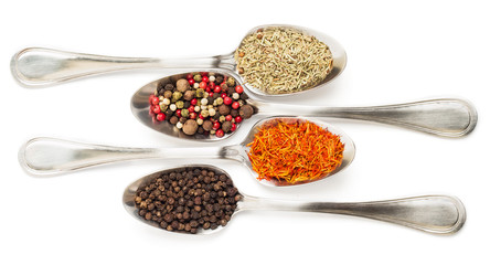 Different spices in iron spoons isolated on white