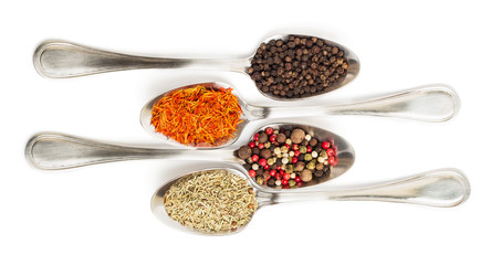 Different spices in iron spoons isolated on white