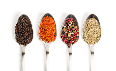 Different spices in iron spoons isolated on white