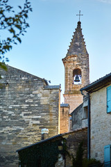 View of the church tower with a bell and a cross and roofs of houses with sitting pigeons