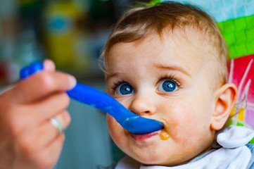 baby boy eating with spoon at home