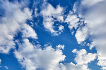 white fluffy soaring clouds on a blue sky background