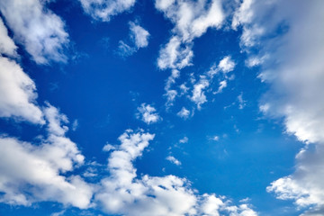 white fluffy soaring clouds on a blue sky background