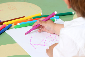 close up on the hand of a child who draws with colored markers