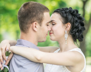 Fototapeta premium Close-up portrait of beautiful young couple female bride and male bridegroom kissing in summer park. Woman wife hugging man husband