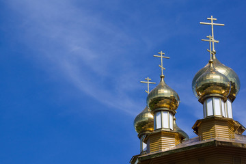 Fototapeta na wymiar Golden domes and crosses of Russian orthodox church on blue sky background