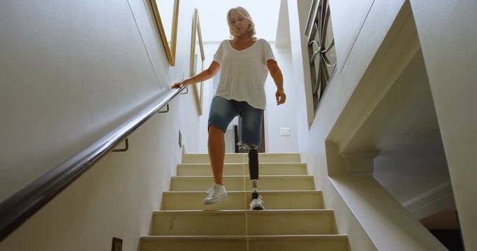 Disabled woman with prosthetic leg moving downstairs 4k