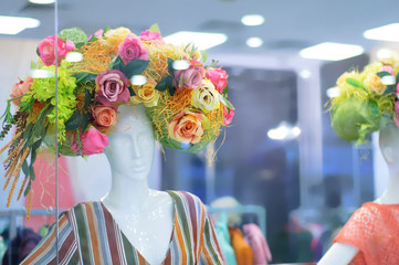 Storefront with mannequins decorated with decorative flowers.