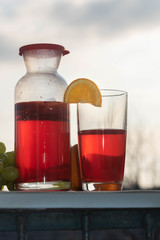 Tasty cold berry tea with fresh grapes, apples and oranges, refreshing homemade summer drink.