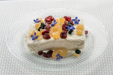 Portion of a quick and healthy cottage cheese snack, colorful dried fruits and edible flowers on top.