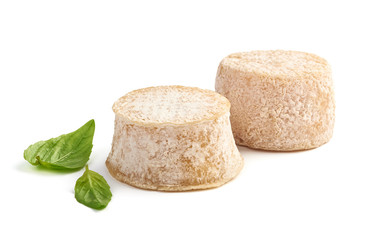 Two Crottin cheese with basil leaves isolated on white background