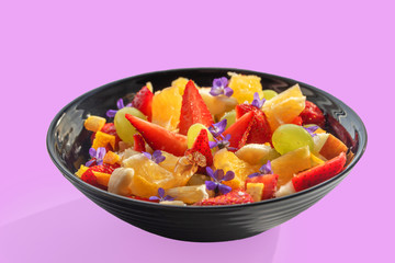 Sweet fruit and berry salad with honey, no sugar added, edible flowers on top