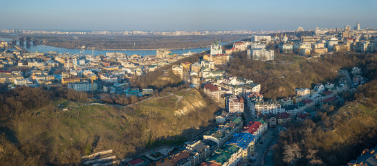 Fototapeta na wymiar A bird's eye view, aerial panoramic view from drone to the Podol district, oldest historical center of Kiev, the Dnieper River and the left bank of Dnieper in the city of Kiev, Ukraine.
