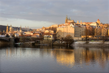 Fototapeta na wymiar Sunny snowy early morning Prague Lesser Town with gothic Castle above River Vltava, Czech republic