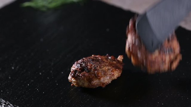 Putting with a tongs meatballs on the dark slate