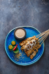 Indonesian chicken skewers sate with peanut sauce and salad, top view, copyspace