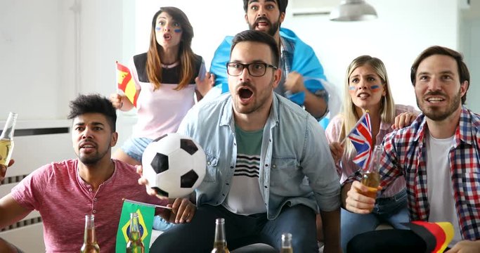 Friends or football fans watching soccer on tv and celebrating victory at home.