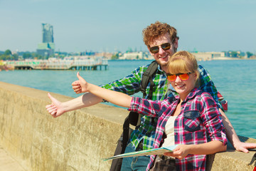 couple backpacker with map by seaside hitchhiking