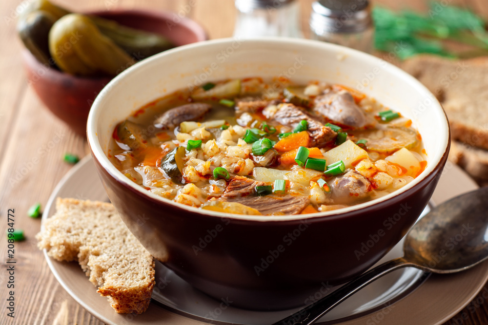 Wall mural Traditional Russian soup Rassolnik with pickled cucumbers and pearl barley in bowl on wooden table