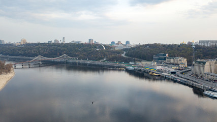 Obraz premium The panoramic bird's eye view shooting from drone of the Podol district, the right bank of the Dnieper River and centre of Kiev, Ukraine summer evening at sunset on the background of the cloudy sky.
