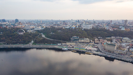 Fototapeta premium The panoramic bird's eye view shooting from drone of the Podol district, the right bank of the Dnieper River and centre of Kiev, Ukraine at summer sunset on the background of the cloudy sky.