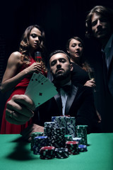 concentrated men and women playing poker in casino