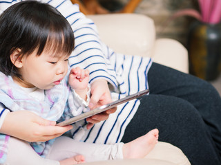 baby girl play tablet on sofa at home