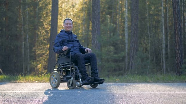 Smiling physically challenged man sitting in a powered wheelchair outdoors