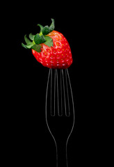 Delicious single Strawberry on a fork outline highlight, black background