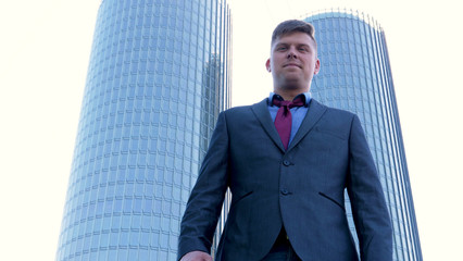 Fototapeta premium Young handsome businessman in suit, skyscraper background