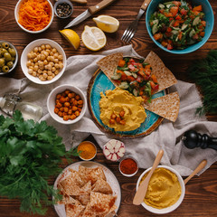 Top view of plate with hummus served with different kinds on vegetables and pita