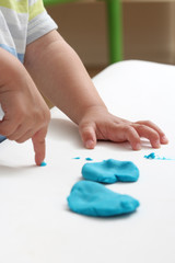 close-up of a child's hand playing with blue and violet modeling clay