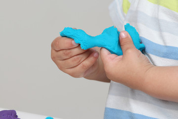 close-up of a child's hand playing with blue and violet modeling clay