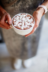 Cocoa with marshmallow in hands.